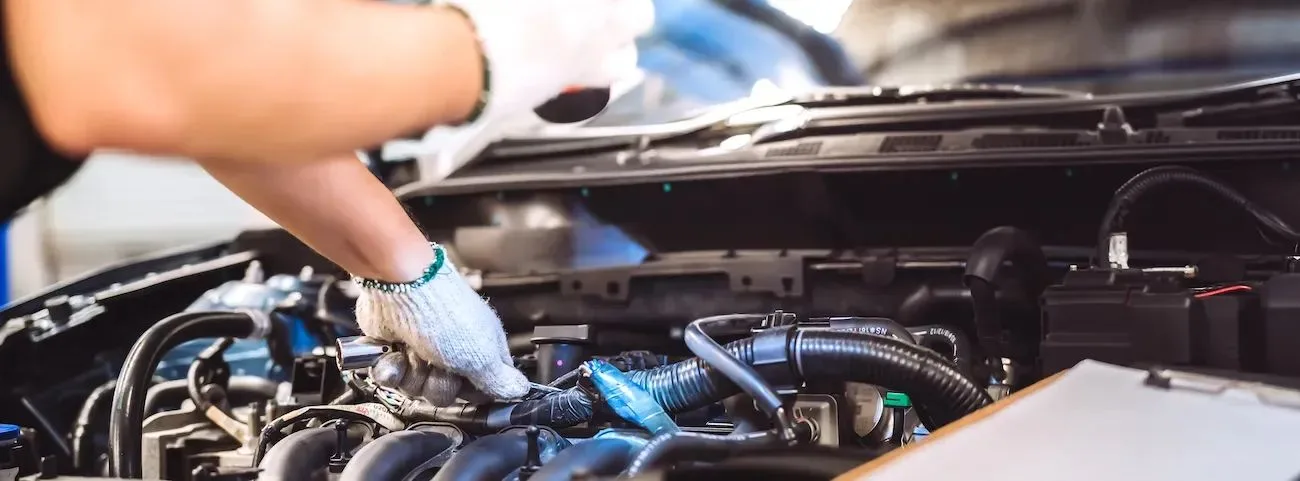 Manos con guantes revisando el motor de un auto